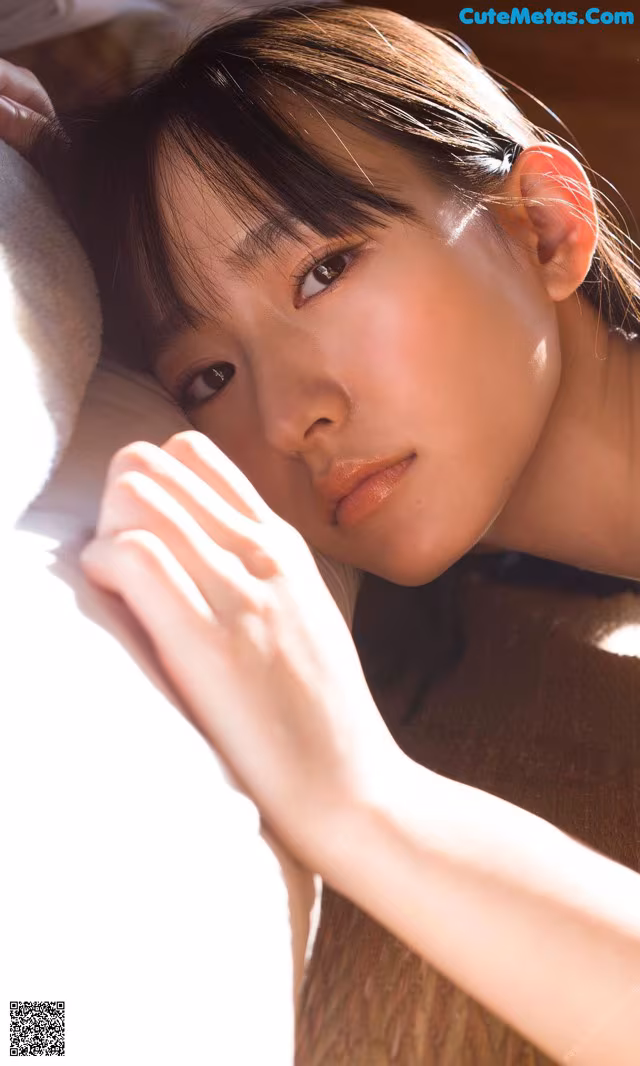 A woman laying on top of a couch next to a pillow.