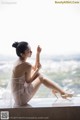 A woman sitting on a window sill with her legs crossed.