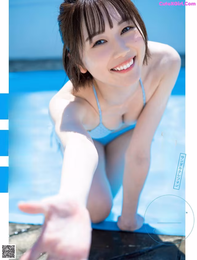 A woman in a blue bikini sitting on the edge of a pool.