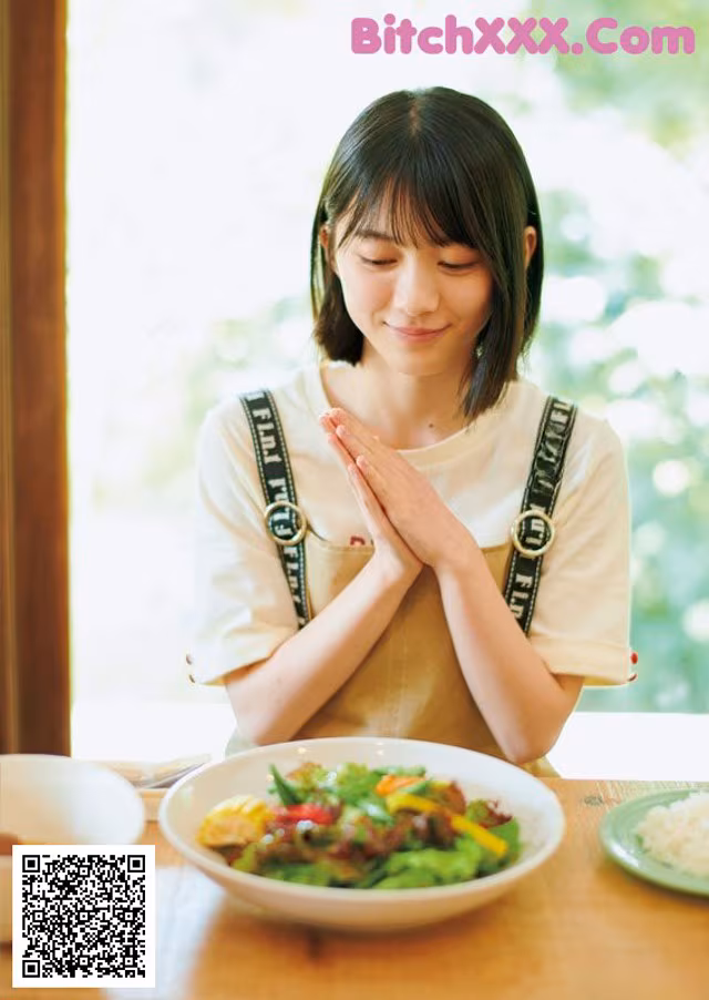 A woman sitting at a table with a plate of food.