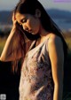 A woman in a floral dress standing in a field.