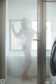 A woman standing in a bathroom next to a washing machine.