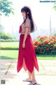 A woman in a long red skirt standing in a park.