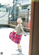 A woman in a pink and blue plaid skirt is walking down the street.