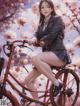 A woman sitting on a bike in front of a flowering tree.