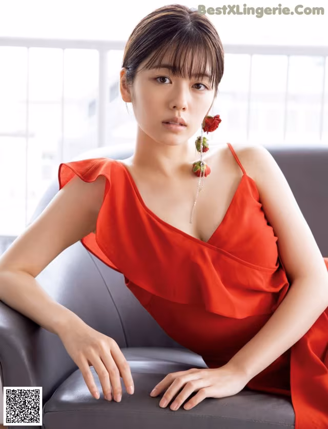 A woman in a red dress sitting on a couch.