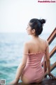 A woman in a pink bathing suit sitting on a pier.