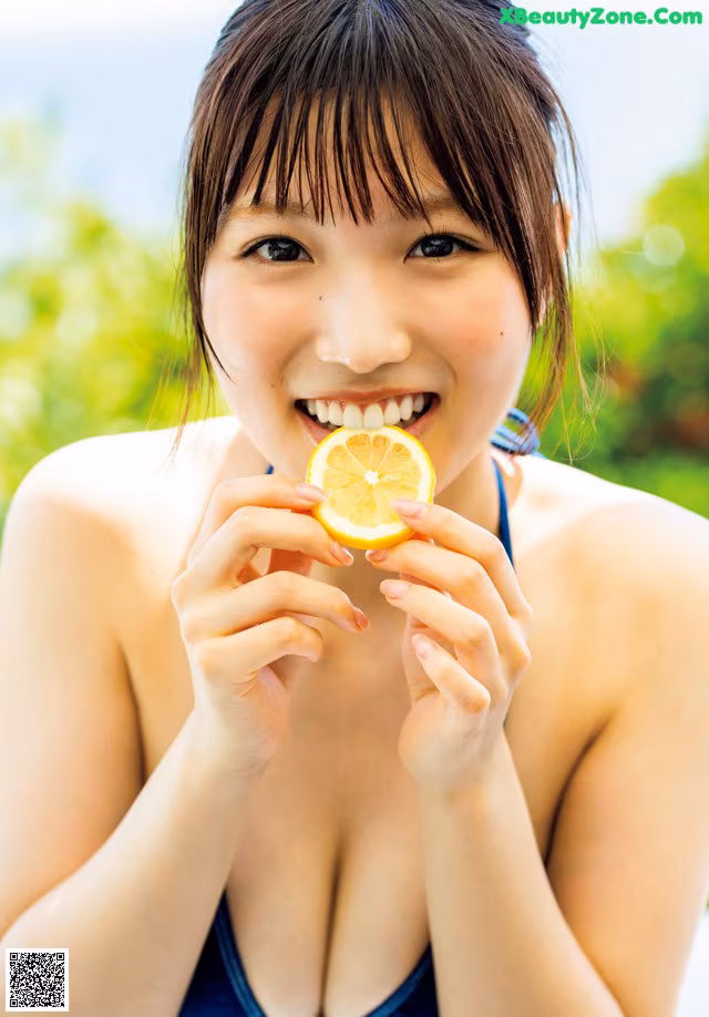 A woman in a blue bikini holding a slice of lemon.