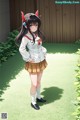 A girl in a school uniform standing in a garden.