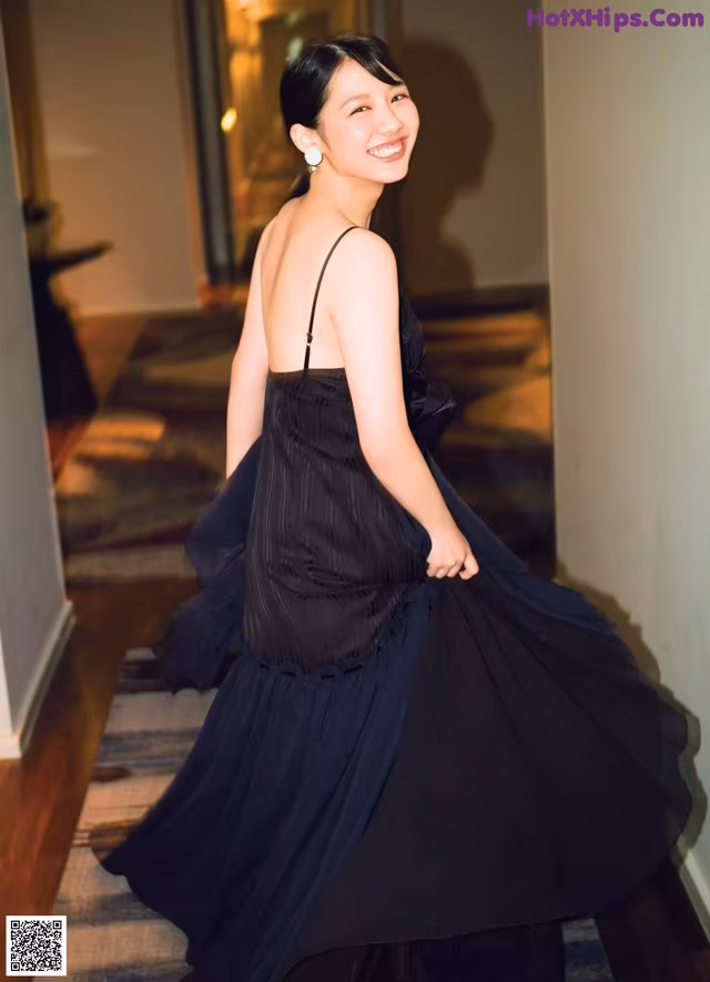 A woman in a black dress standing in a hallway.