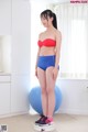 A woman in a red top and blue shorts standing on a scale.