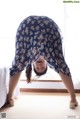 A woman in a blue floral dress doing a handstand on a bed.