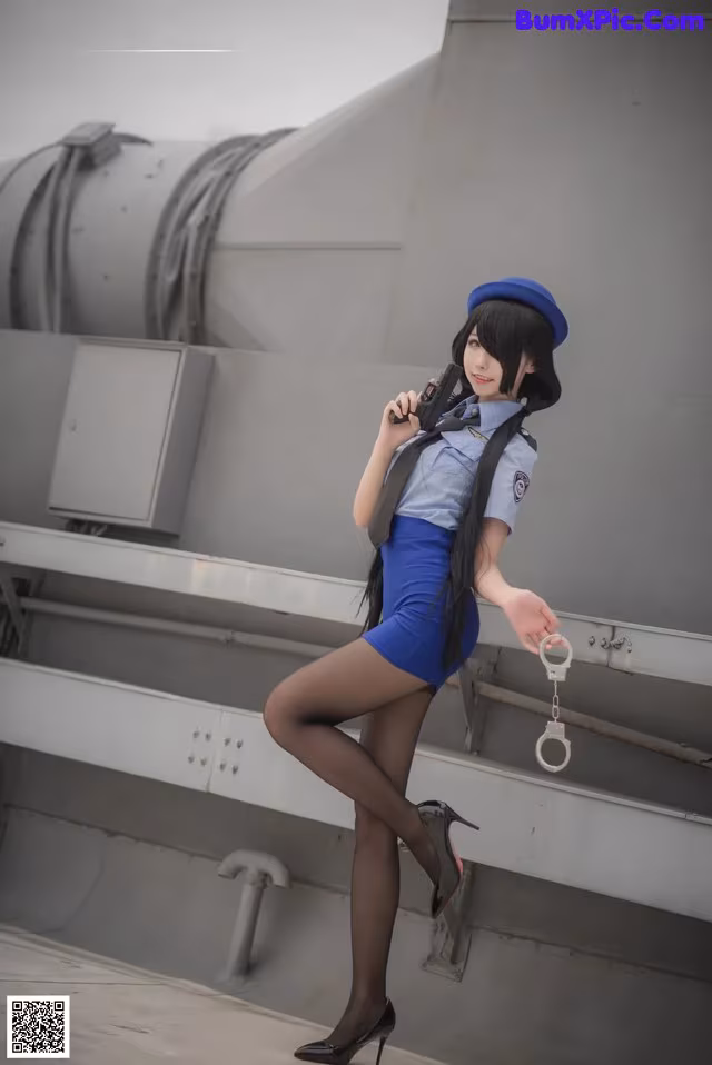 A woman in a blue dress and hat holding a gun.