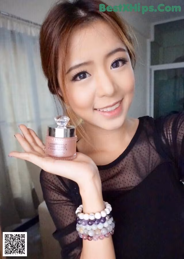 A woman holding a bottle of perfume in her hand.