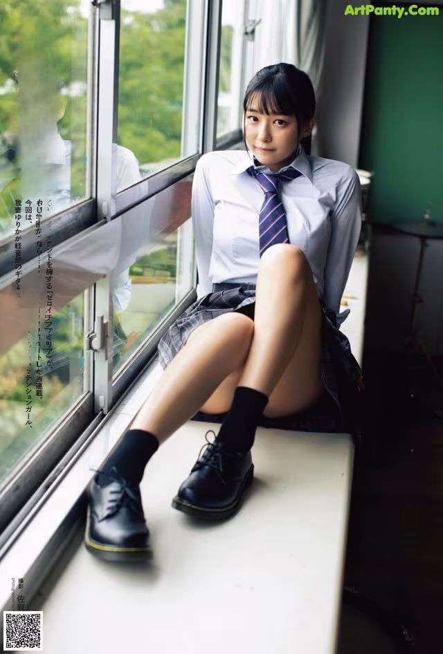 A woman in a school uniform sitting on a window sill.