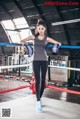 A woman standing in a boxing ring holding a pair of boxing gloves.