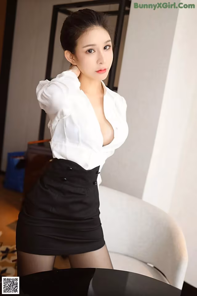 A woman in a white shirt and black skirt posing for the camera.