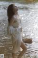 A woman in a white dress standing in the water.