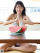 A woman sitting at a table with a plate of watermelon.