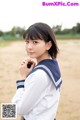 A woman in a school uniform holding a cell phone.