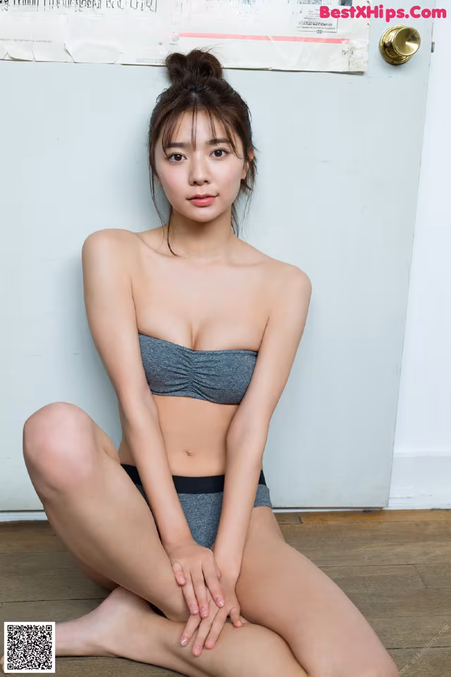 A woman in a gray bikini sitting on the floor.