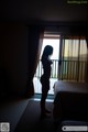 A naked woman standing in front of a window in a hotel room.