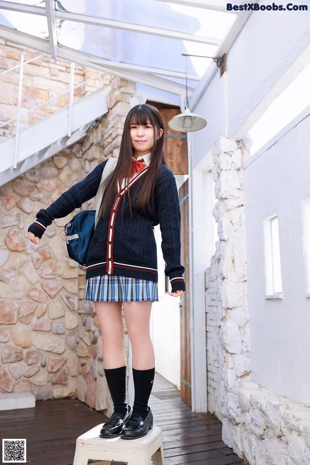A woman in a school uniform standing on a stool.