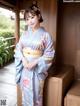 A woman in a blue kimono posing for a picture.