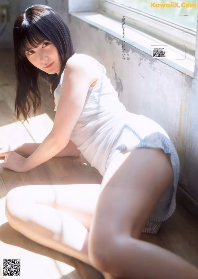 A woman sitting on the floor in front of a window.