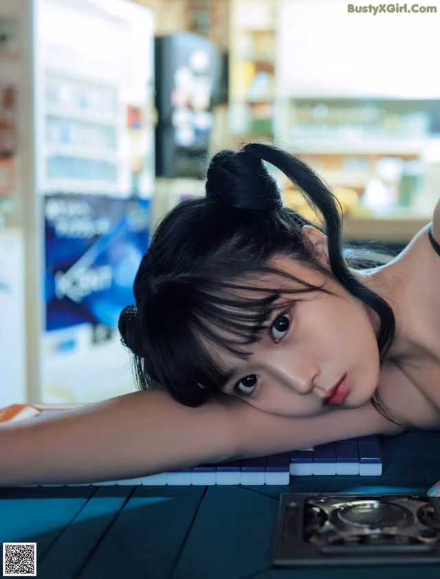 A woman laying on top of a table next to a keyboard.